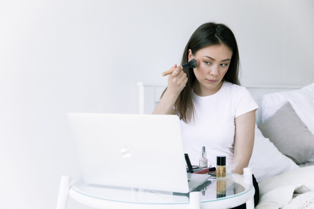 a woman trying makeup while attending the online course