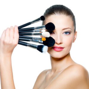 a model with different makeup brushes in her hand
