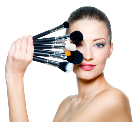 a model with different makeup brushes in her hand