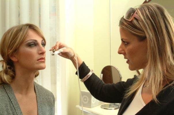 A woman applying airbrush make up on another woman